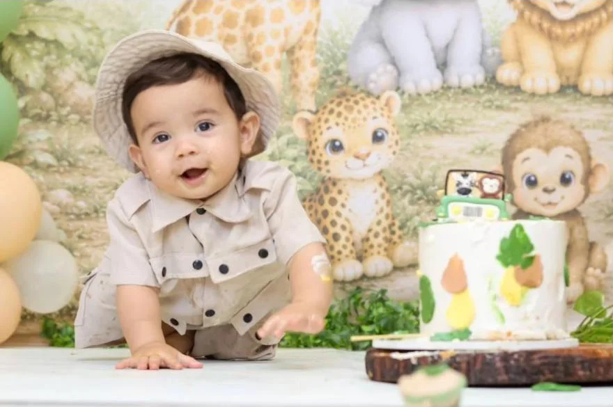 Bebê de chapéu sorrindo em cenário de safári